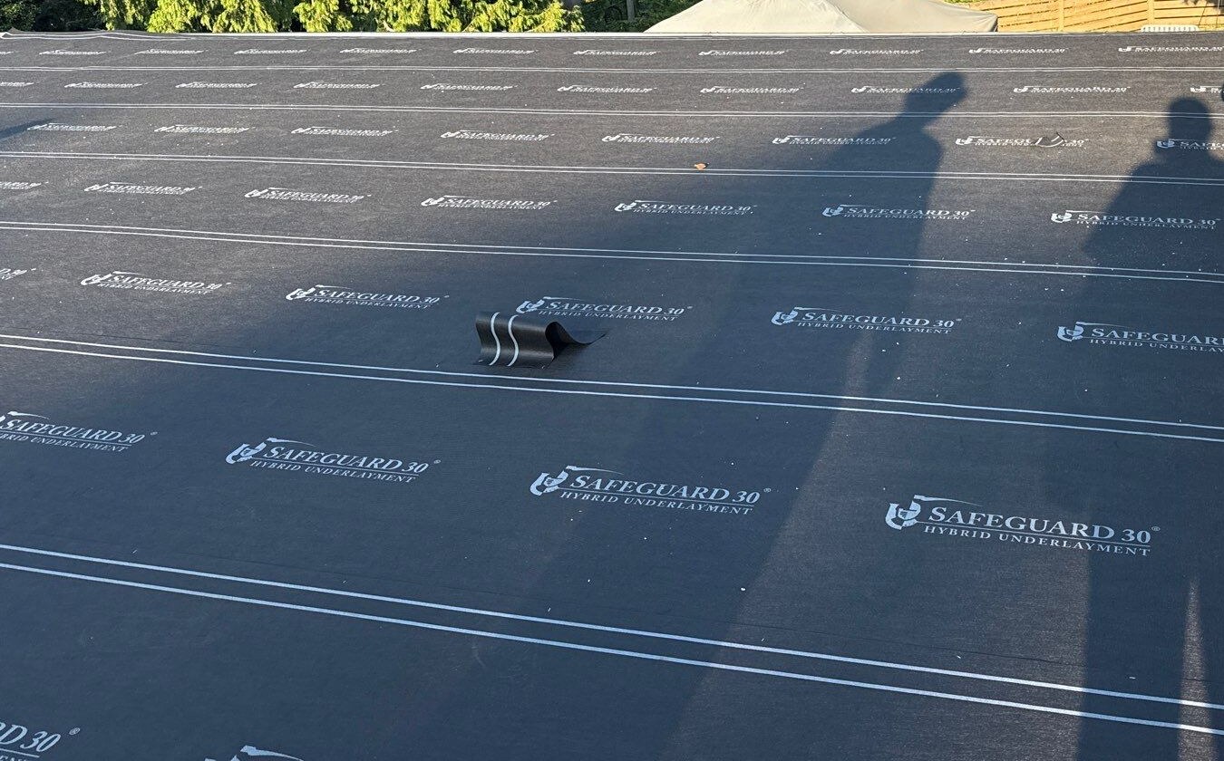 Dark underlayment across a low-slope roof with parallel printed lines