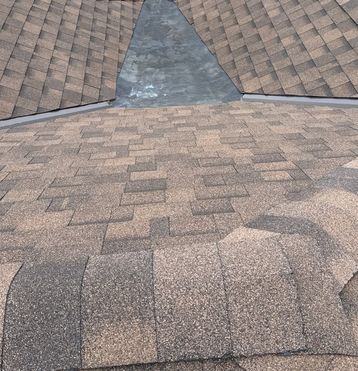 Brown shingle slopes adjoining a dark center at a roof junction