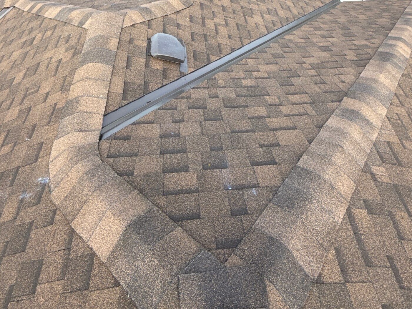 Completed brown composition-shingle roof planes, ridges and junction